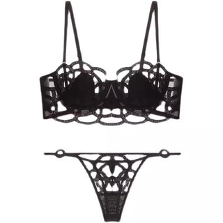 The Petite Cherry Jolie Unlined Transparent Lace Bra and Thong Set features exquisite lace detailing and sheer transparency. This black lingerie set includes a bra with multiple straps and intricate, web-like patterns, along with a matching thong. The elaborate design adds a sophisticated and seductive touch to the ensemble.